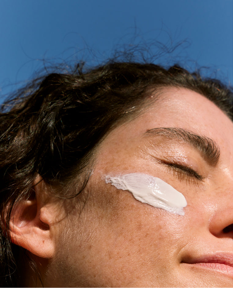 Close-up of a person with sunscreen on their face against a blue sky.
